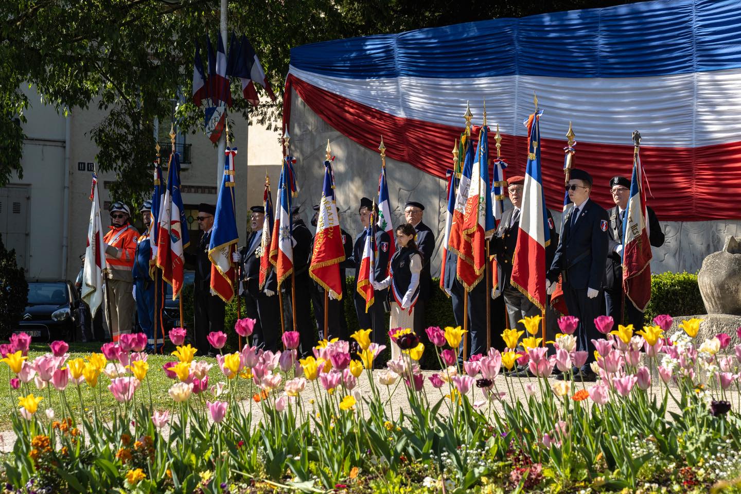 Cérémonie patriotique à Troyes avec porte-drapeaux devant une façade tricolore